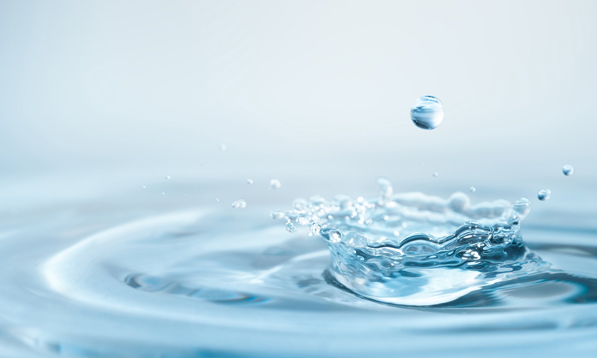 Macro drop falling onto the surface of the water, leaving a splash of water