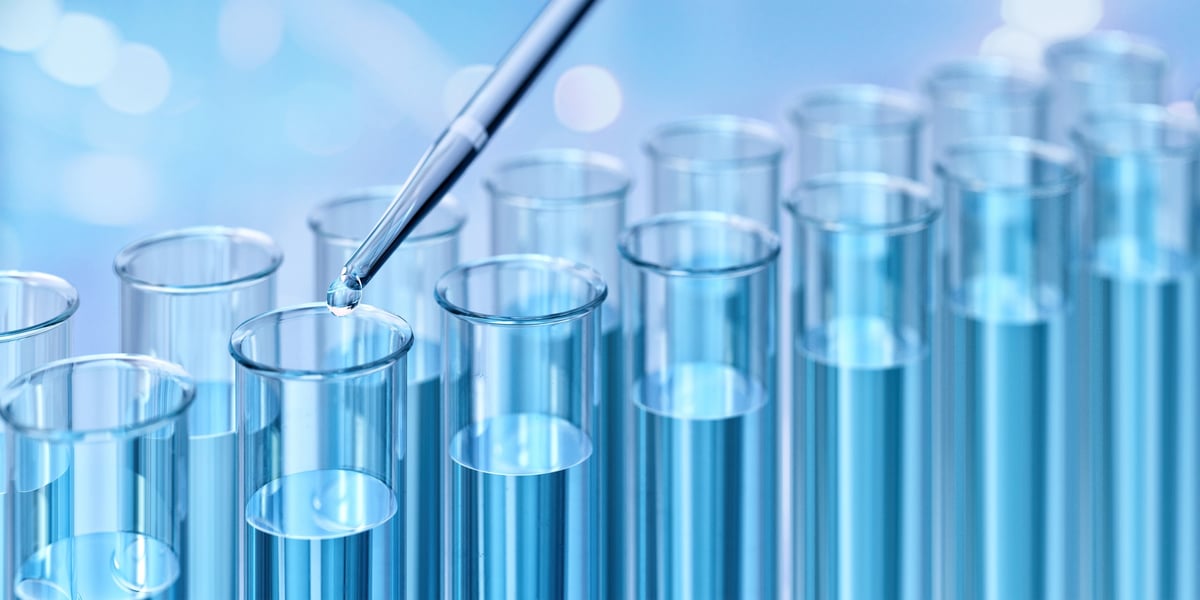 Test tubes filled with blue liquid. A pipette is dispensing a droplet. Scientific chemistry research, analysis. Laboratory setting