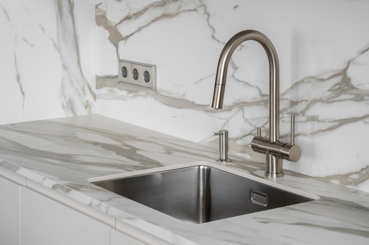 Premium modern kitchen with stainless steel sink, marble countertop and minimalist tap — home water filtration comparison