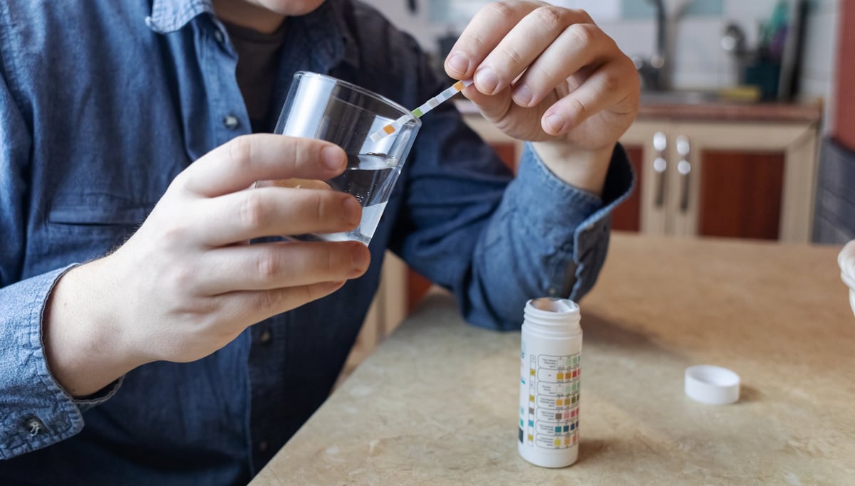 Person testing drinking water safety for pH, chlorine, and chemical contaminants at home